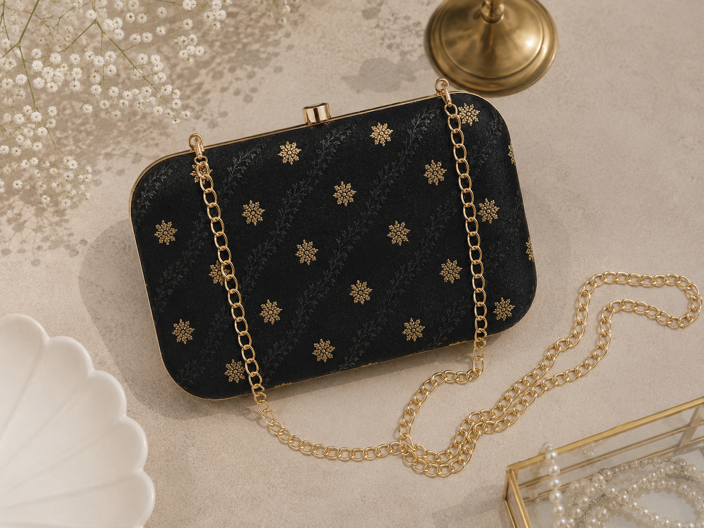 Jet black brocade clutch bag with floral butti patterns, detachable gold chain, and metallic frame for festive and party wear for womens