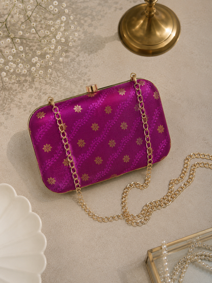 Magenta pink brocade clutch bag with floral butti patterns, detachable gold chain, and metallic frame for festive and wedding wear