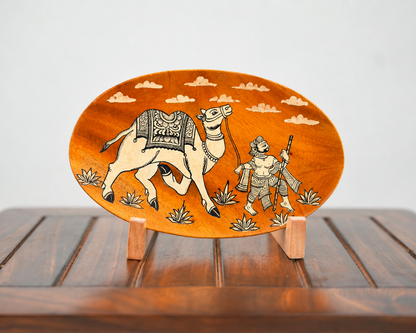 An oval wooden plaque featuring an inlaid design of a camel and a warrior under a cloudy sky, displayed on a wooden stand.